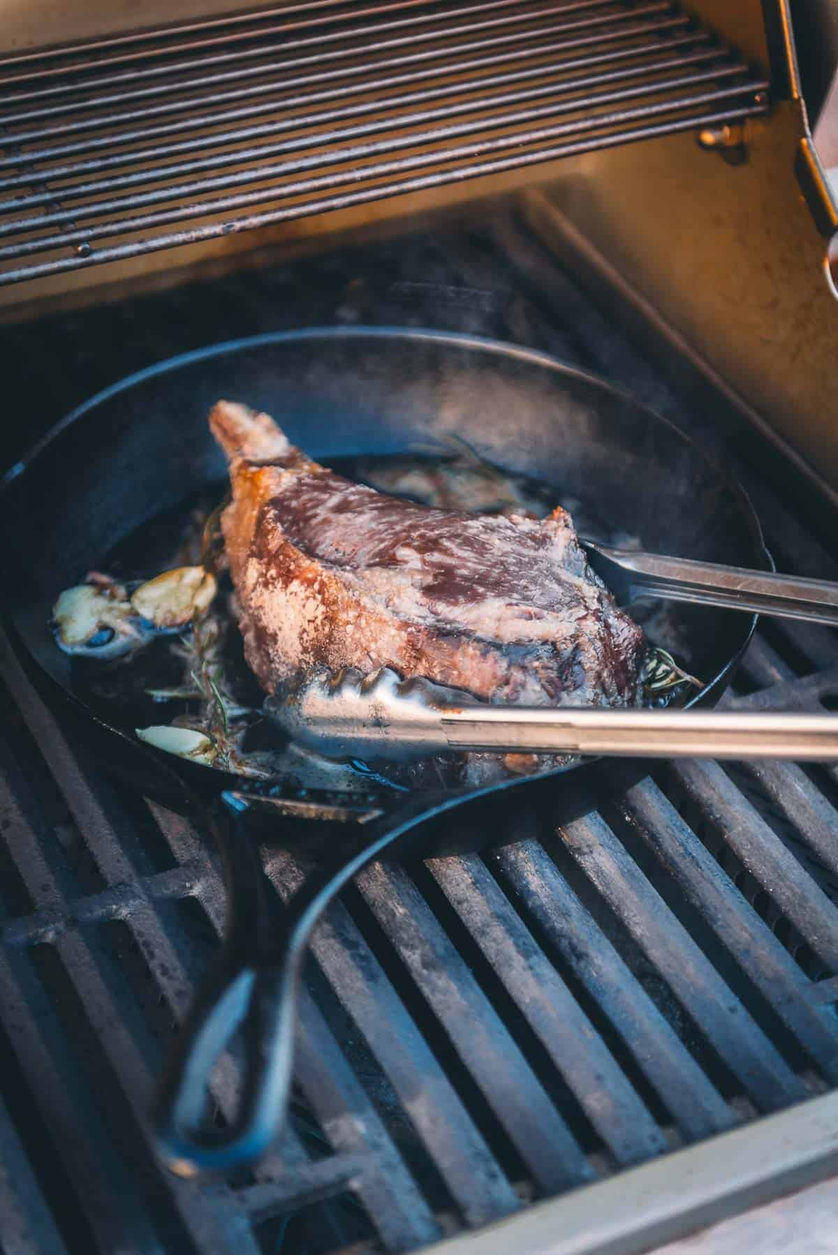 Steak being placed in cast iron skillet. 