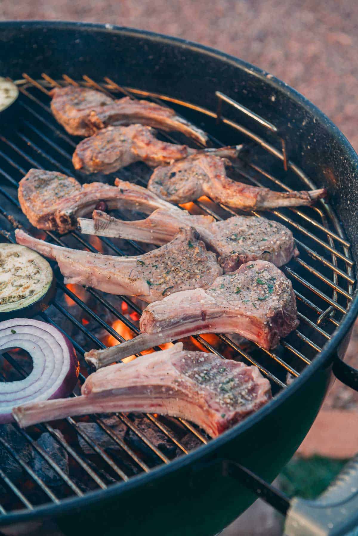 Lamb ribs on a grill grate over charcoal.