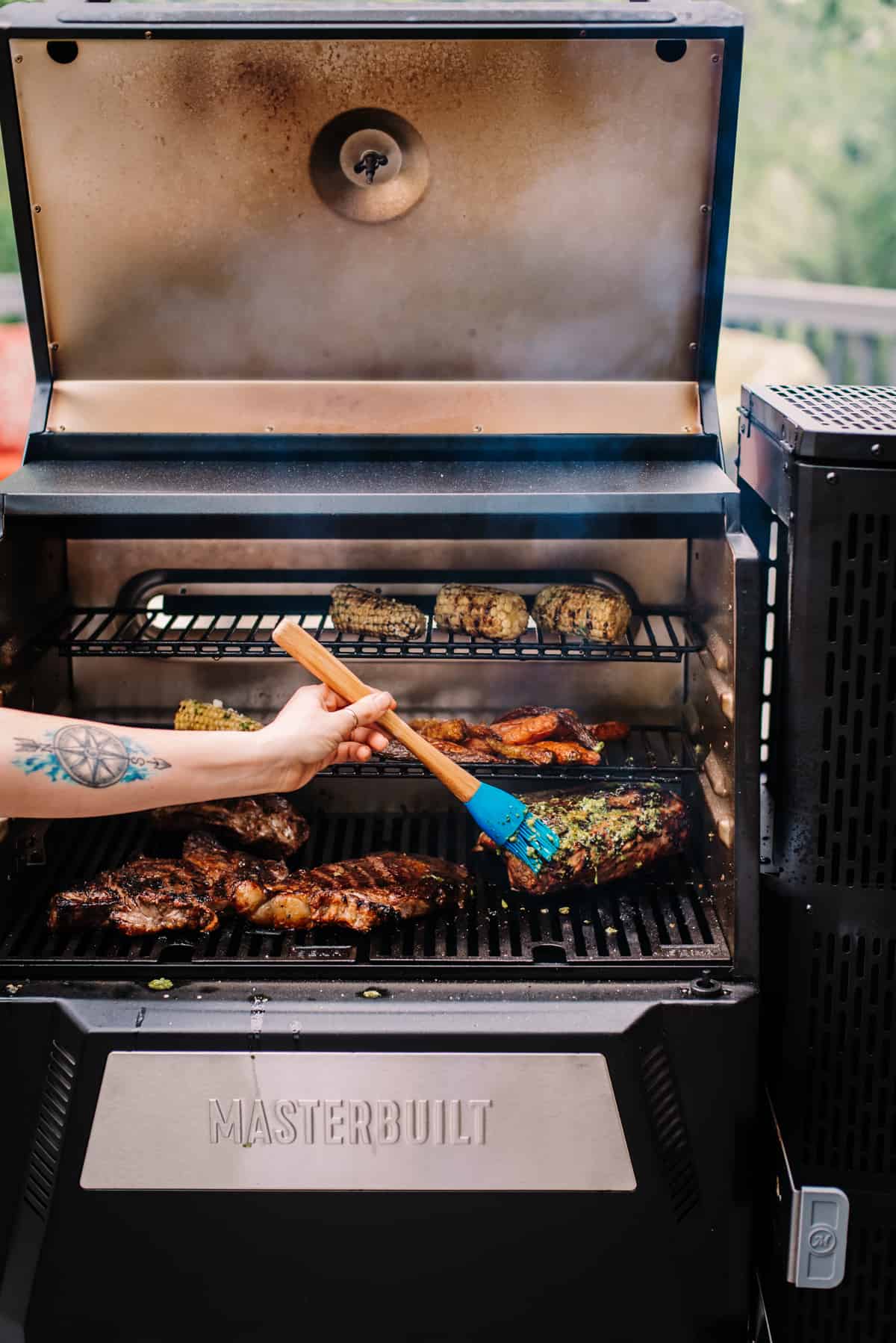 Hand using brush to baste meat ona 
 fully loaded grill. 