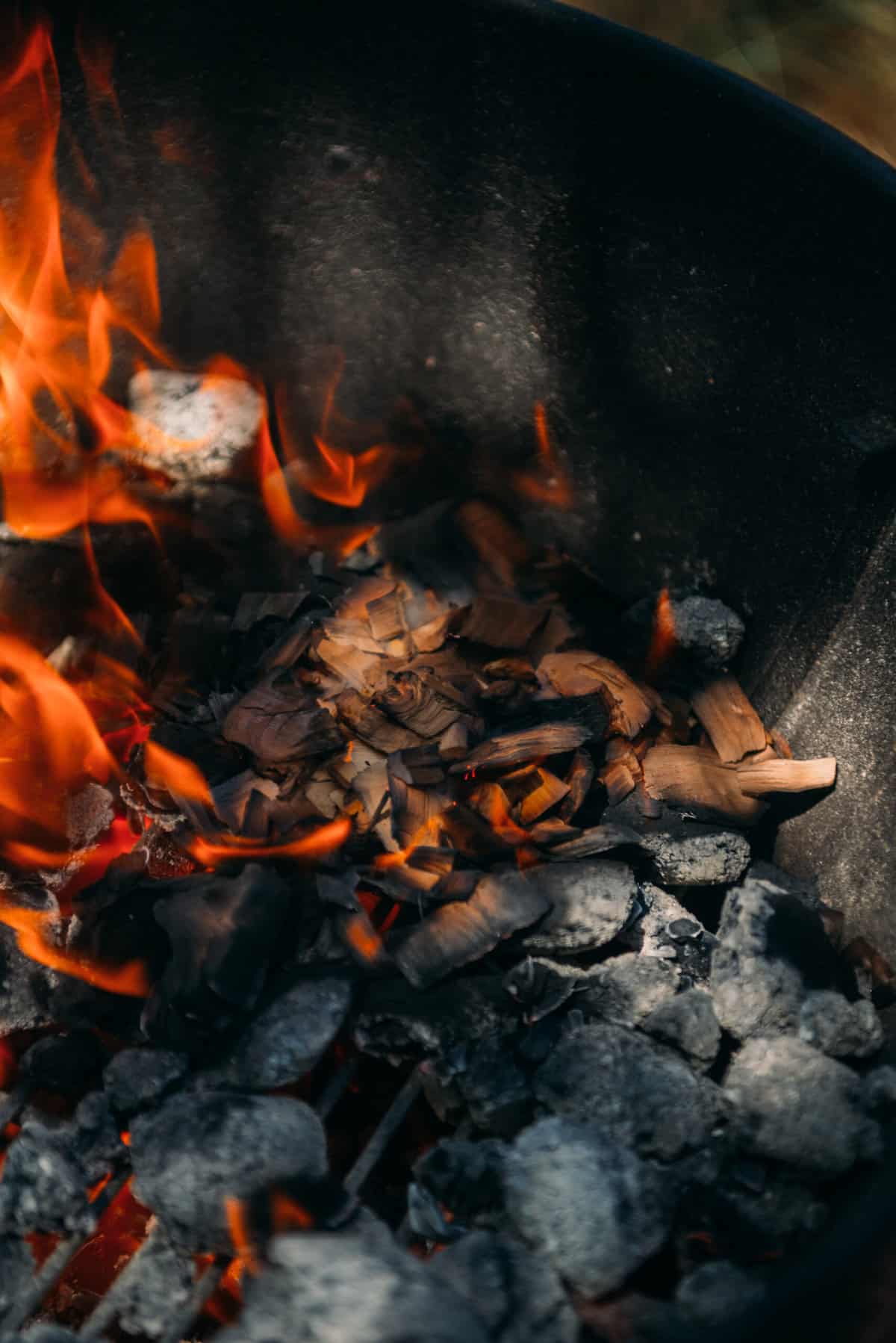Wood chips starting to smoke on a charcoal fire. 