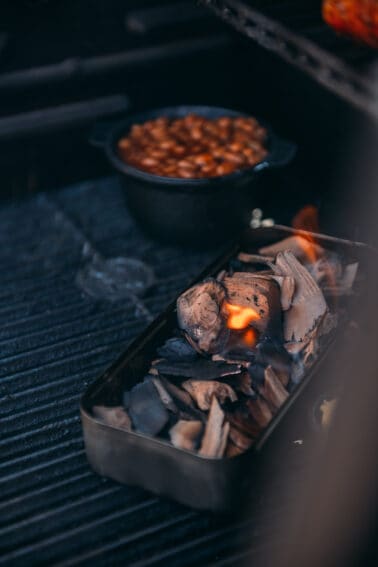 A tray full of smoking wood on a grill.
