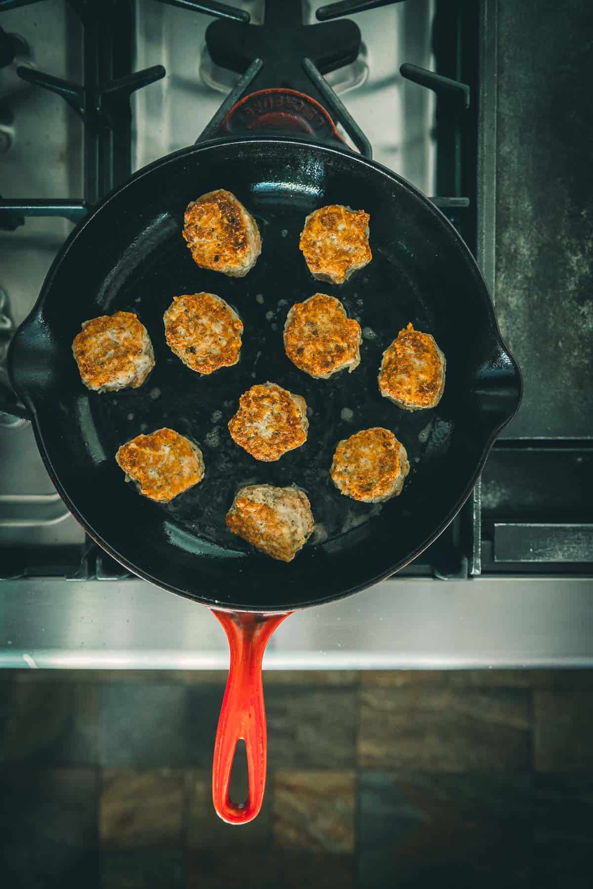 Browned meatballs flipped in the skillet. 