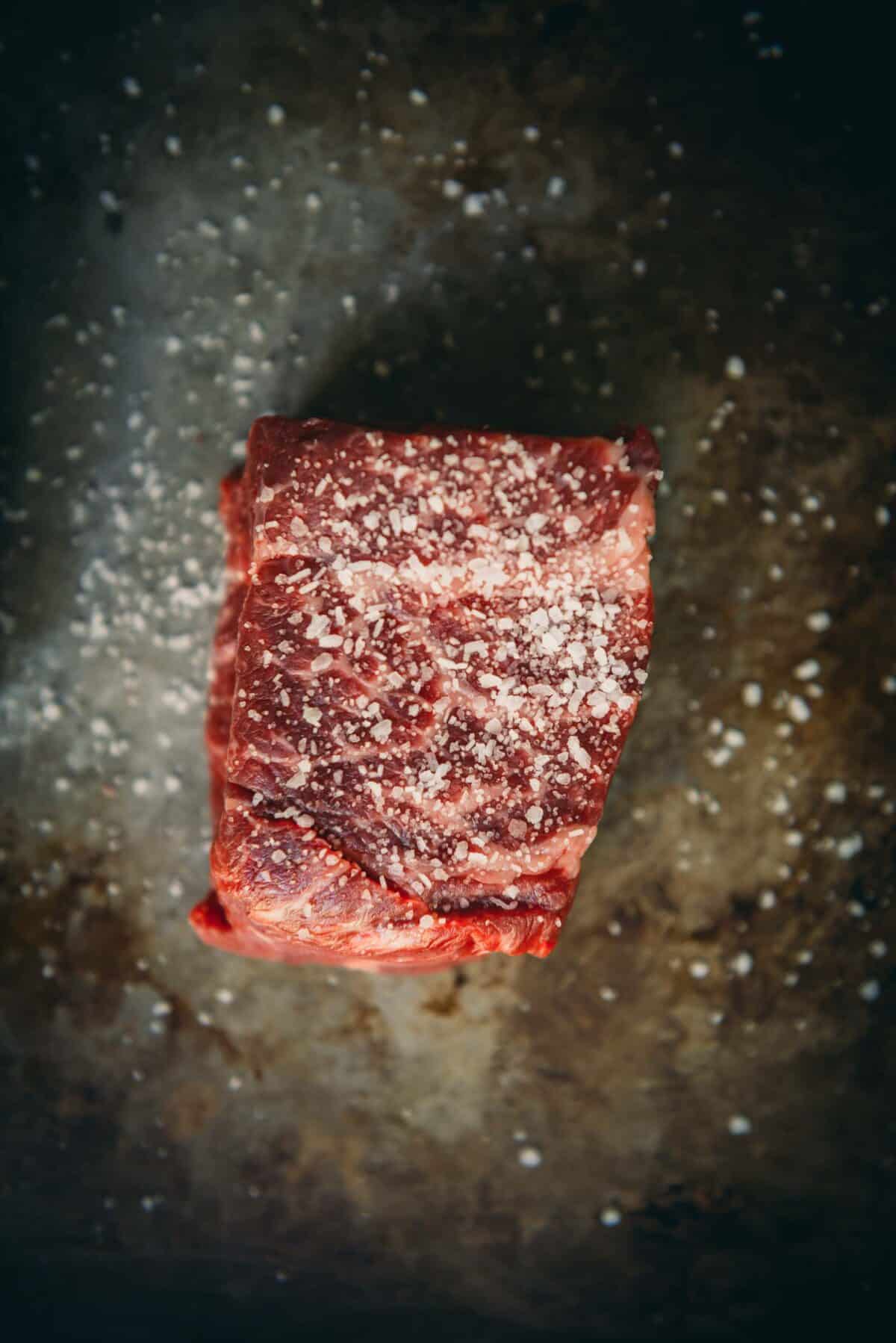 Steak coated with salt and resting. 