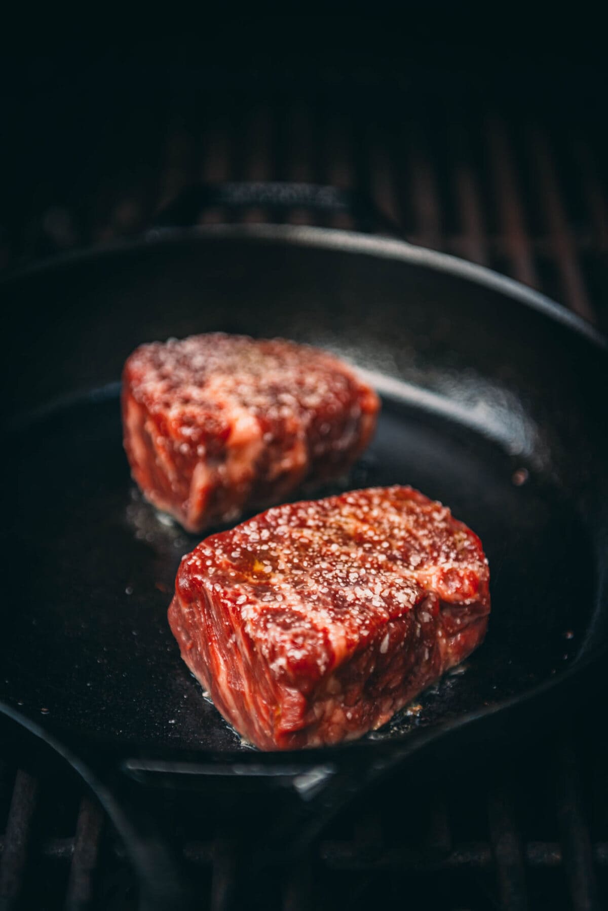 Raw steaks hitting a hot cast iron skillet.