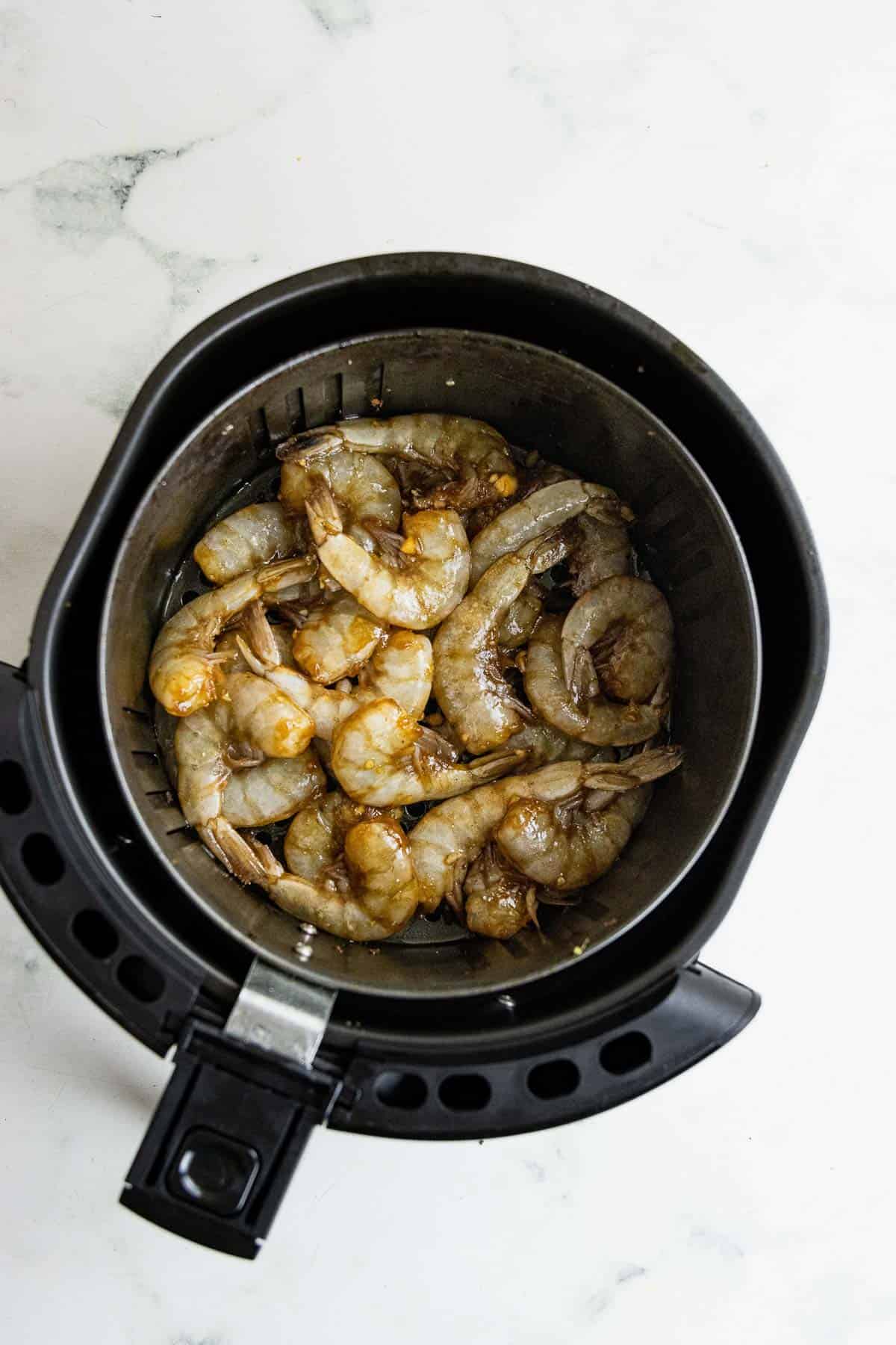 Raw shrimp in the air fryer basket.