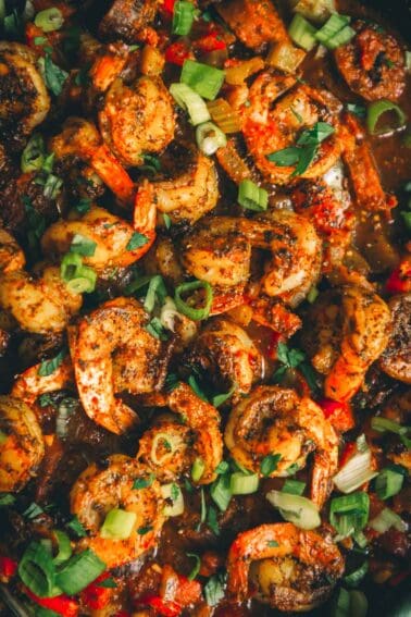 Close up of bright red cooked shrimp in chunky tomato red gravy.