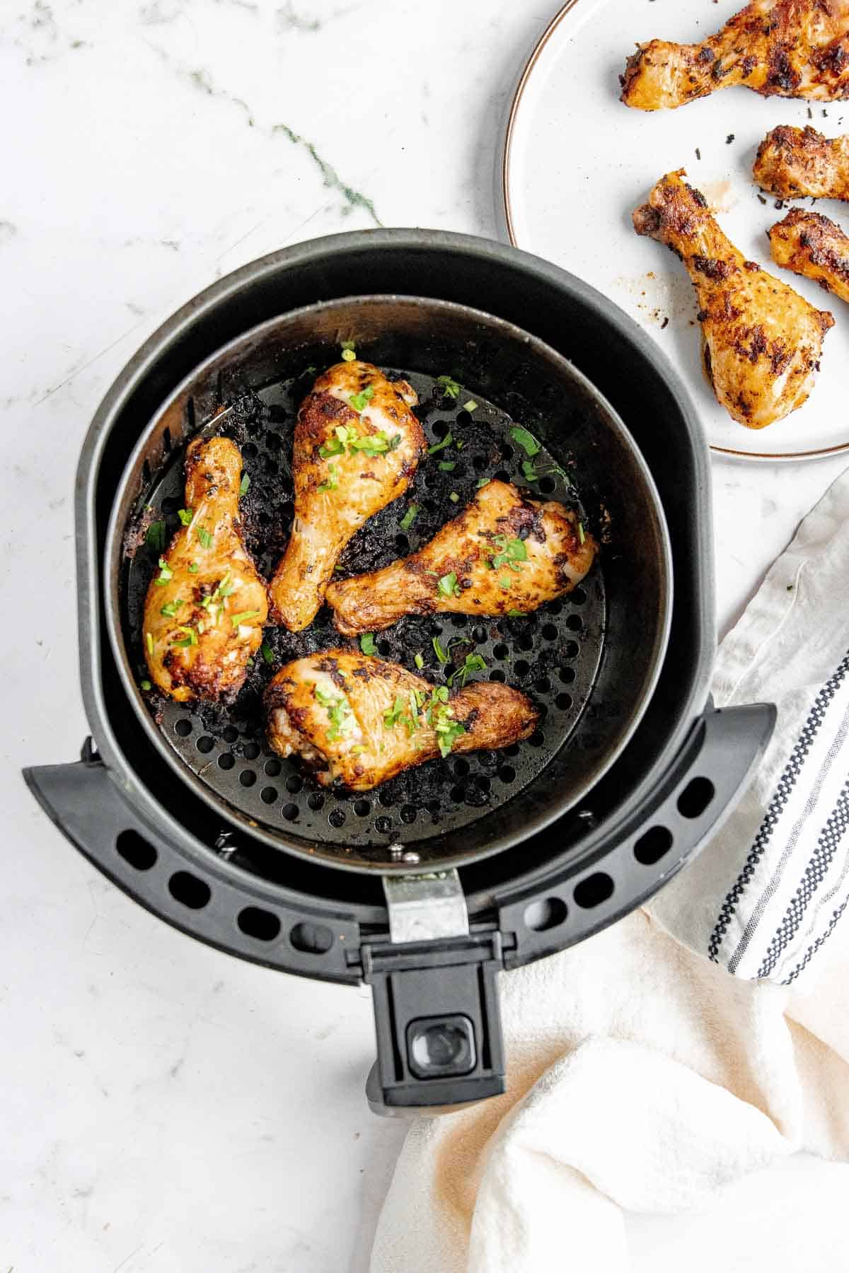Cooked chicken drumsticks in an air fryer basket ready to be eaten. 