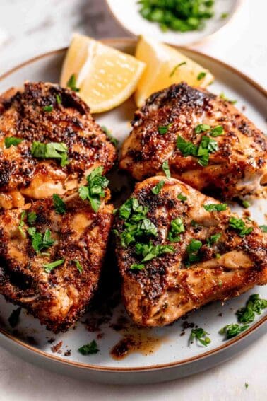 Juicy golden brown chicken garnished with fresh parsley and lemon wedges.