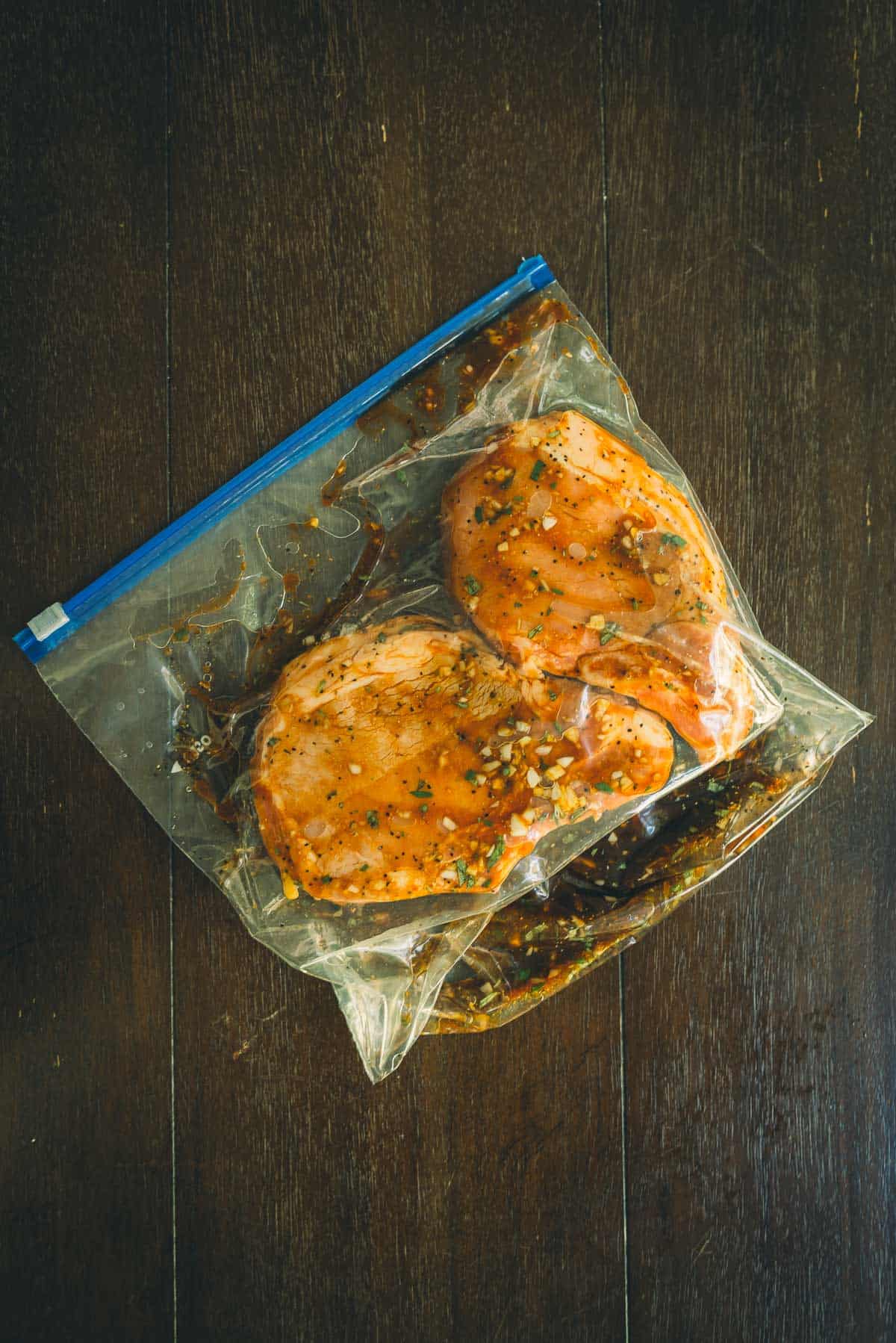 Bone-in pork chops marinating in a plastic bag.