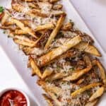 Platter of fries on a white plate with ketchup on the side.