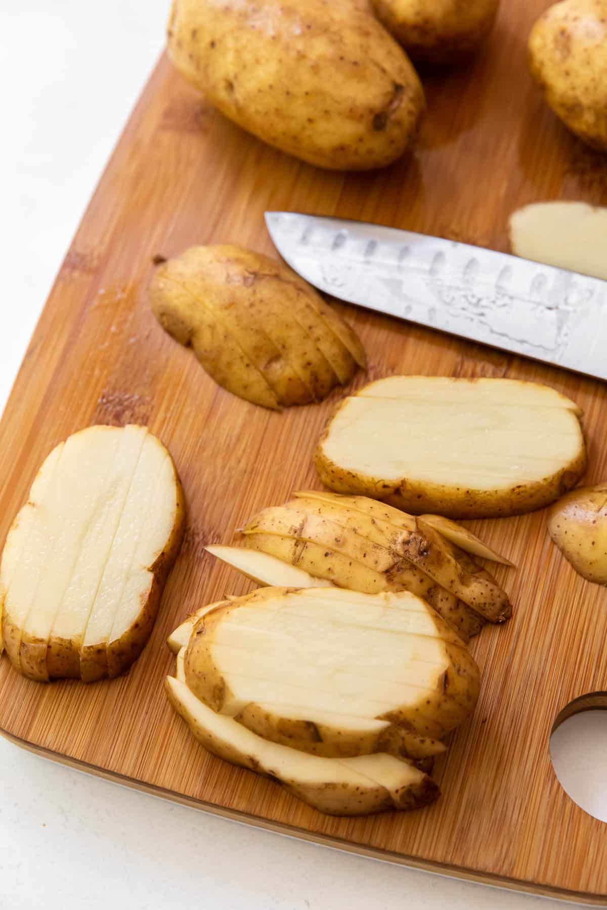 Russet potatoes sliced into strips on a cutting board. 