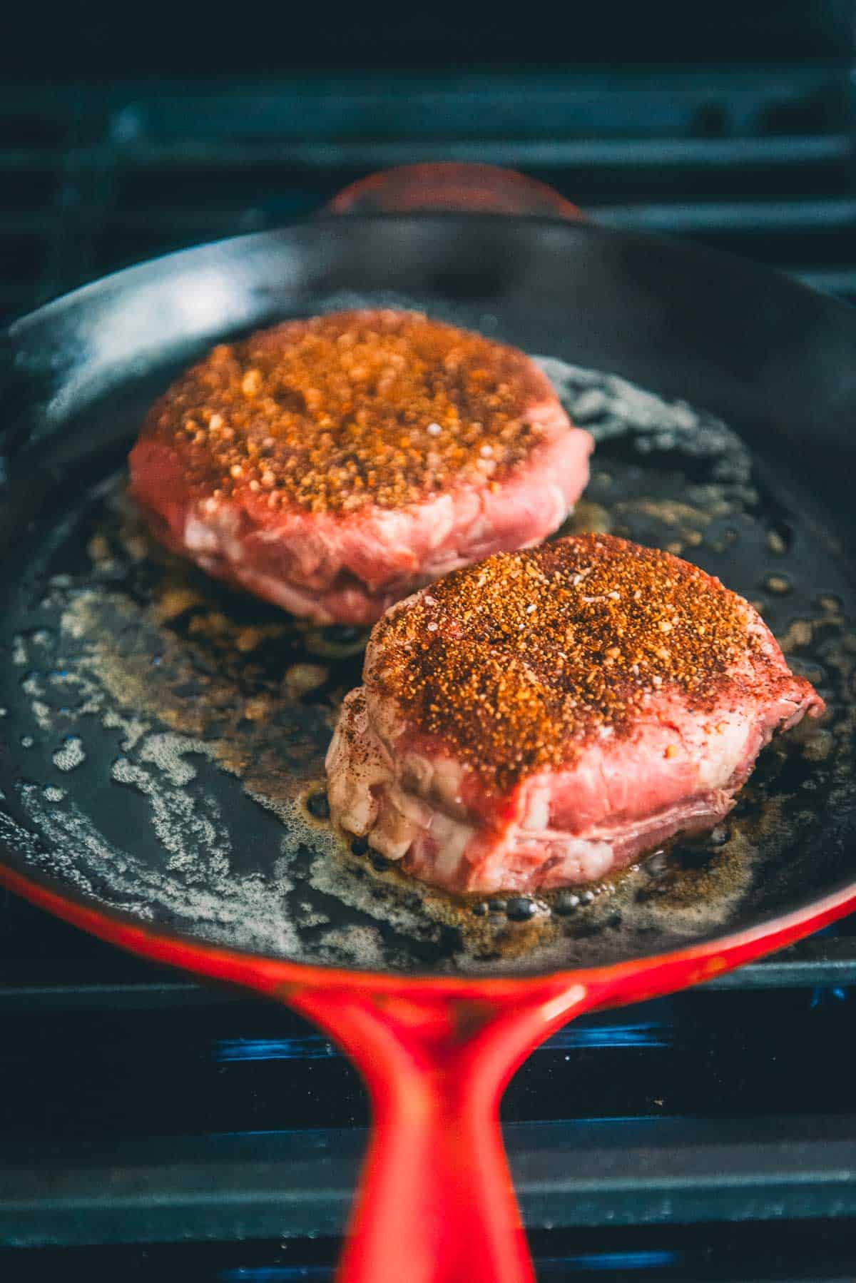 Image of sous vide steaks in cast iron, coated in spices to sear.