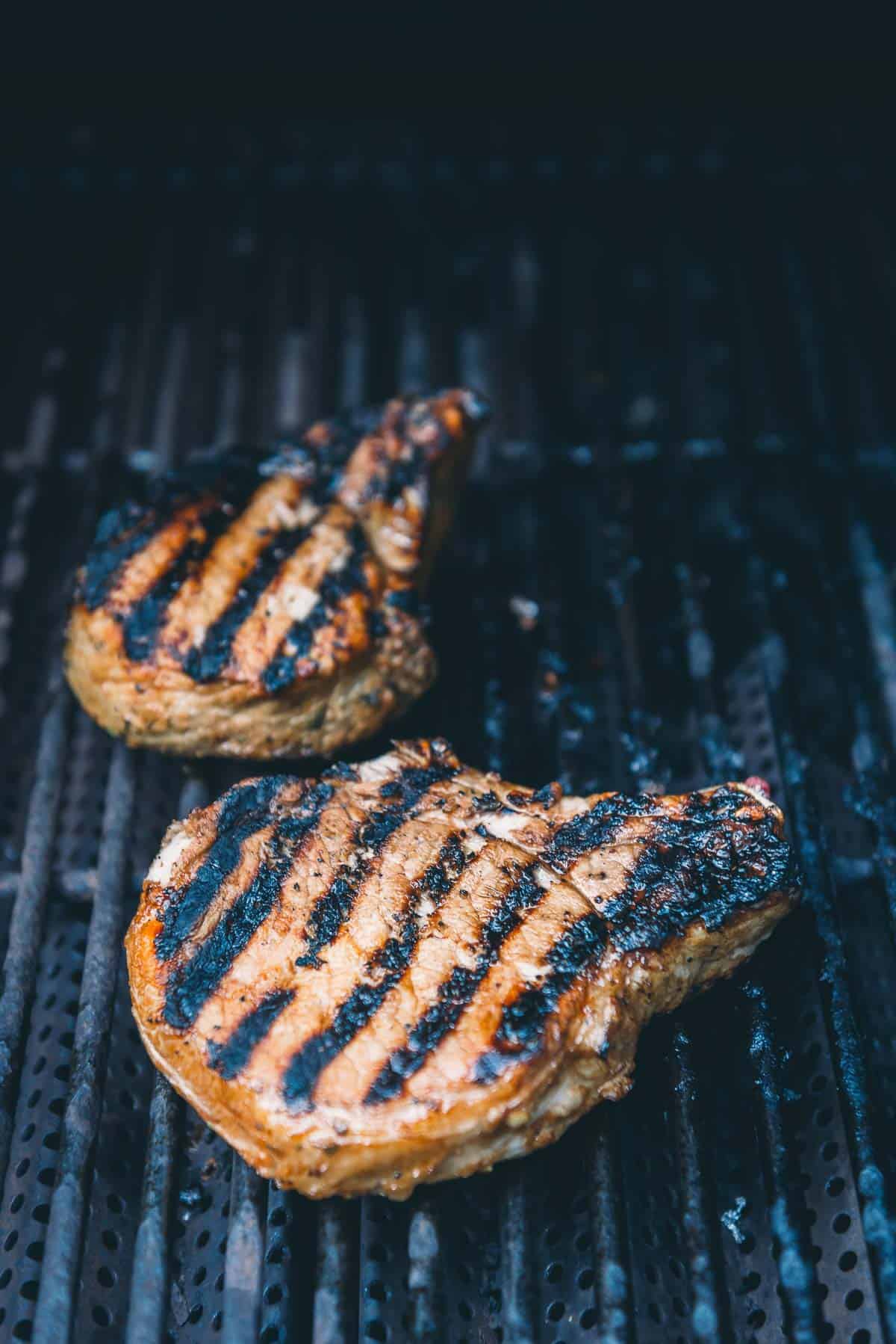 Pork chops flipped on the grill to show grill marks.
