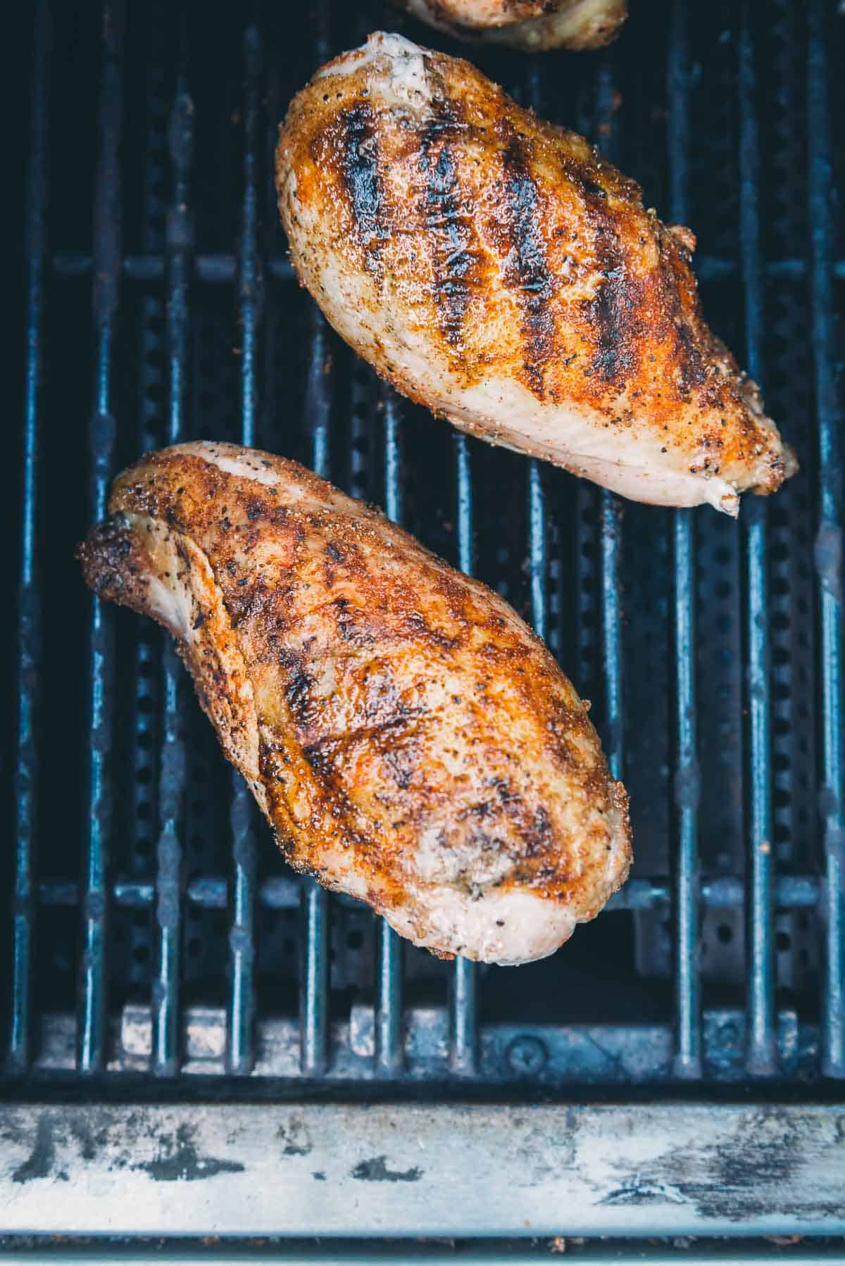 Chicken breast on grill grates, showing grill marks.