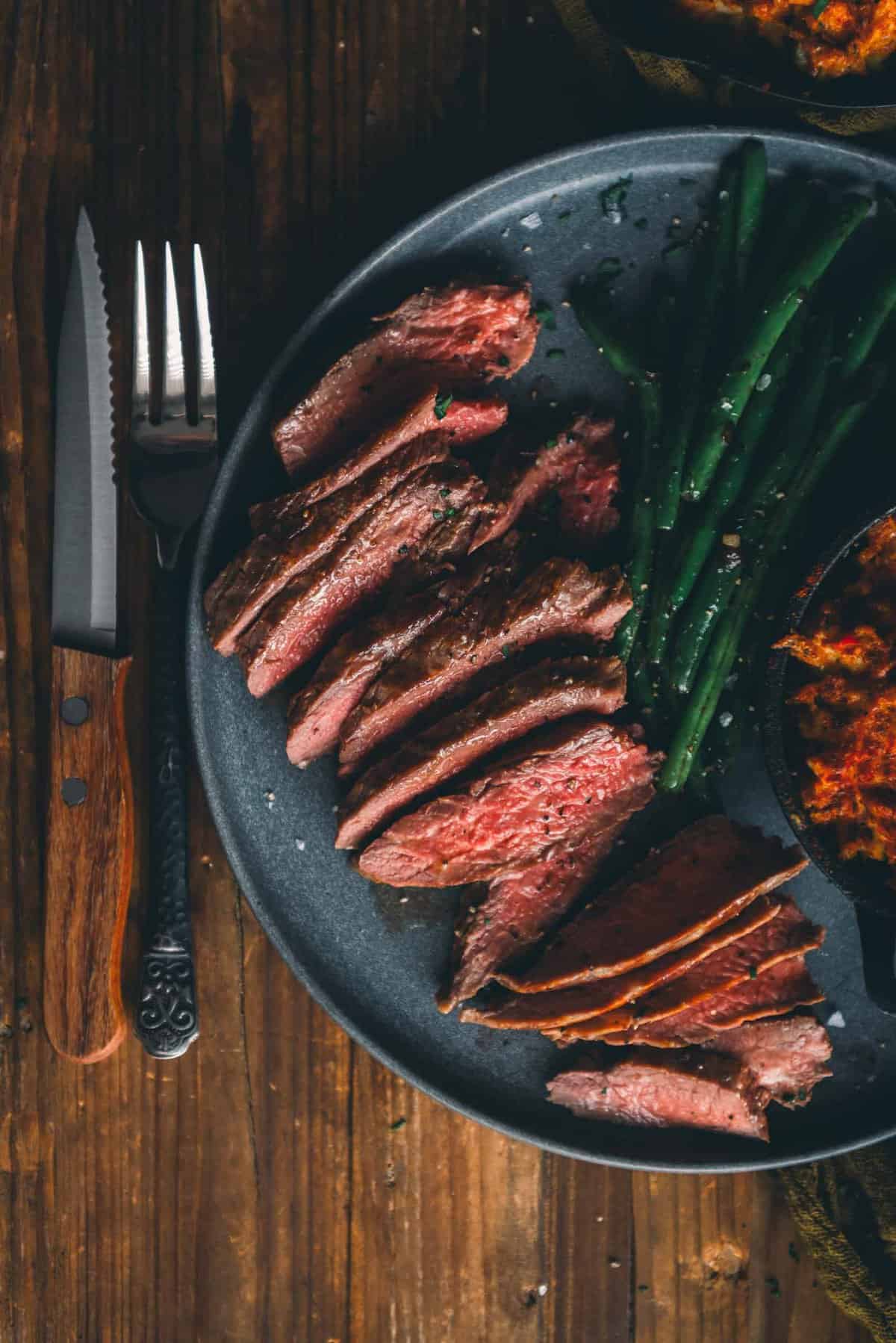 Sliced medium rare blade steak on a plate showing a rose-pink center.