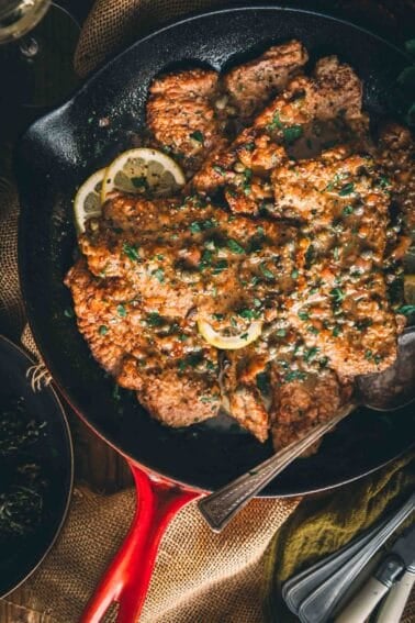 Veal piccata in a skillet with lemon and herbs.