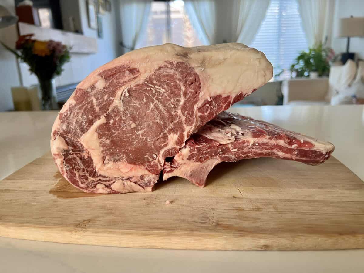 A prime rib roast is sitting on a cutting board, bones sliced off.