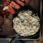 A cast iron skillet with a steak and salad on it.