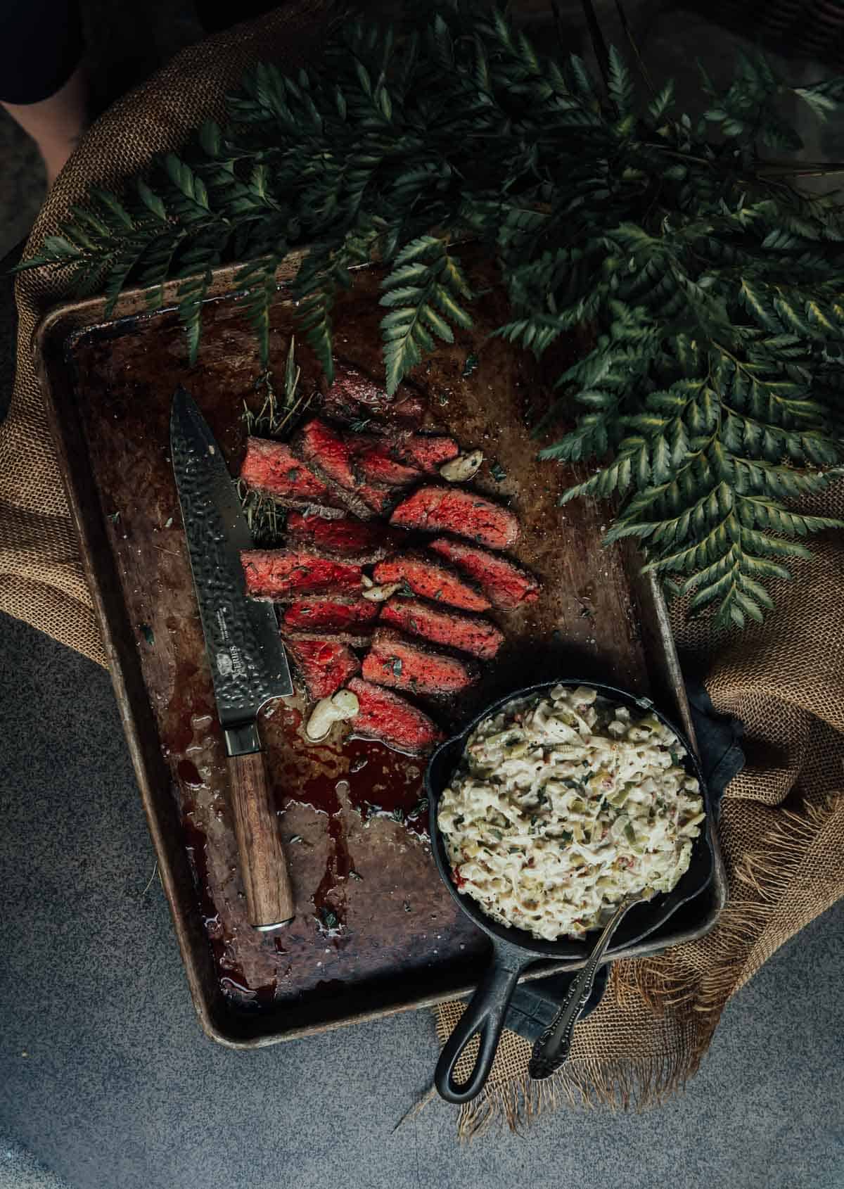 A steak on a tray with rice and a knife.