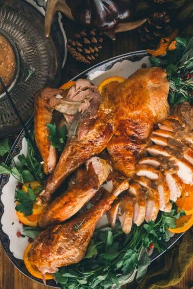 Carving a roasted turkey breast into even slices on a wooden board with a carving knife and fork.