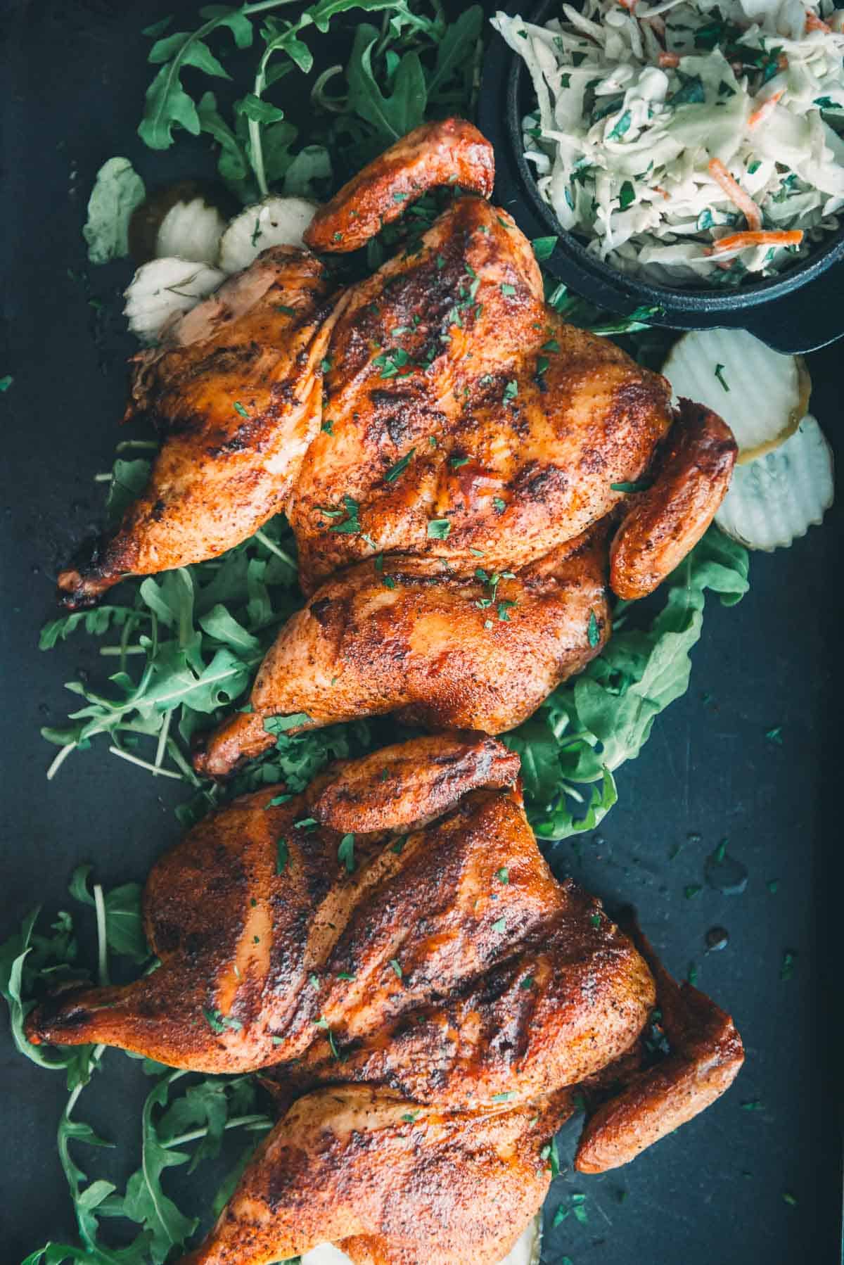 Smoked cornish hens with coleslaw on a baking sheet.