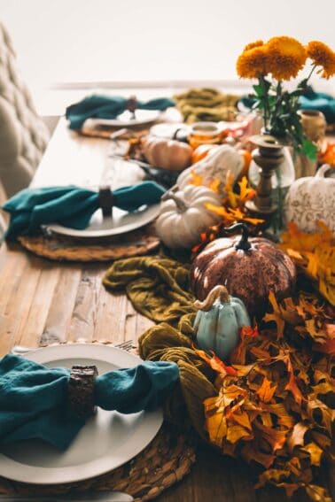 Thanksgiving table setting with pumpkins and leaves.