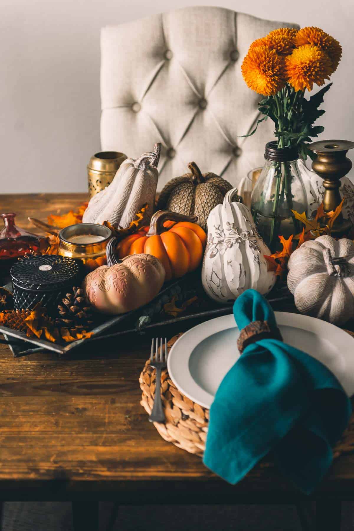 Thanksgiving table setting with pumpkins and flowers.