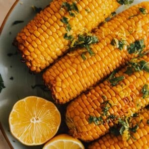 Grilled corn on the cob with lemon slices.
