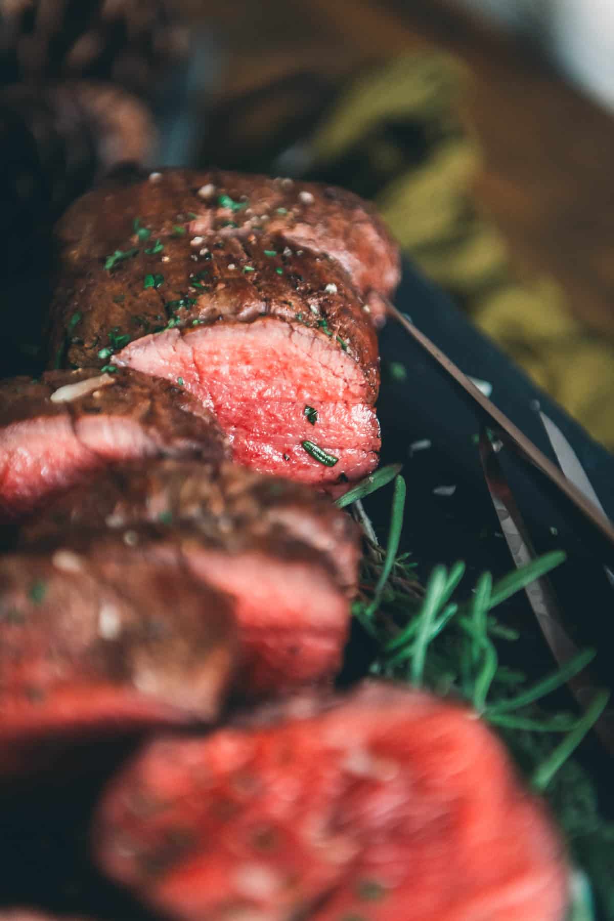 Sliced roast to show the exposed juicy tenderloin with a pink center.