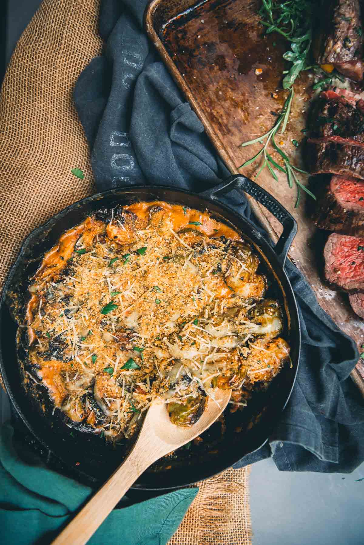 A skillet full of brussels au gratin on a table.