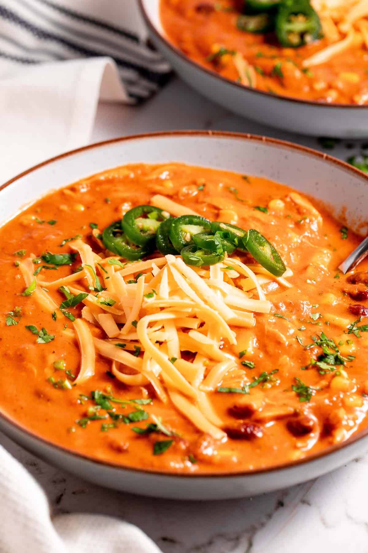 Two bowls of enchilada soup with cheese and jalapenos.