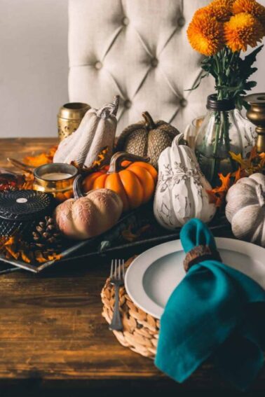 Thanksgiving table setting with pumpkins and flowers.