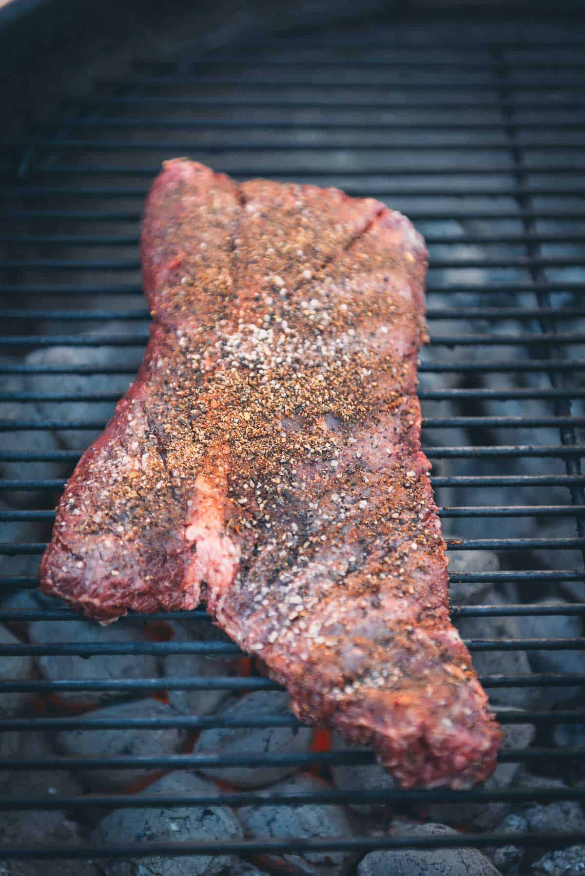 A piece of steak is being cooked on a grill.