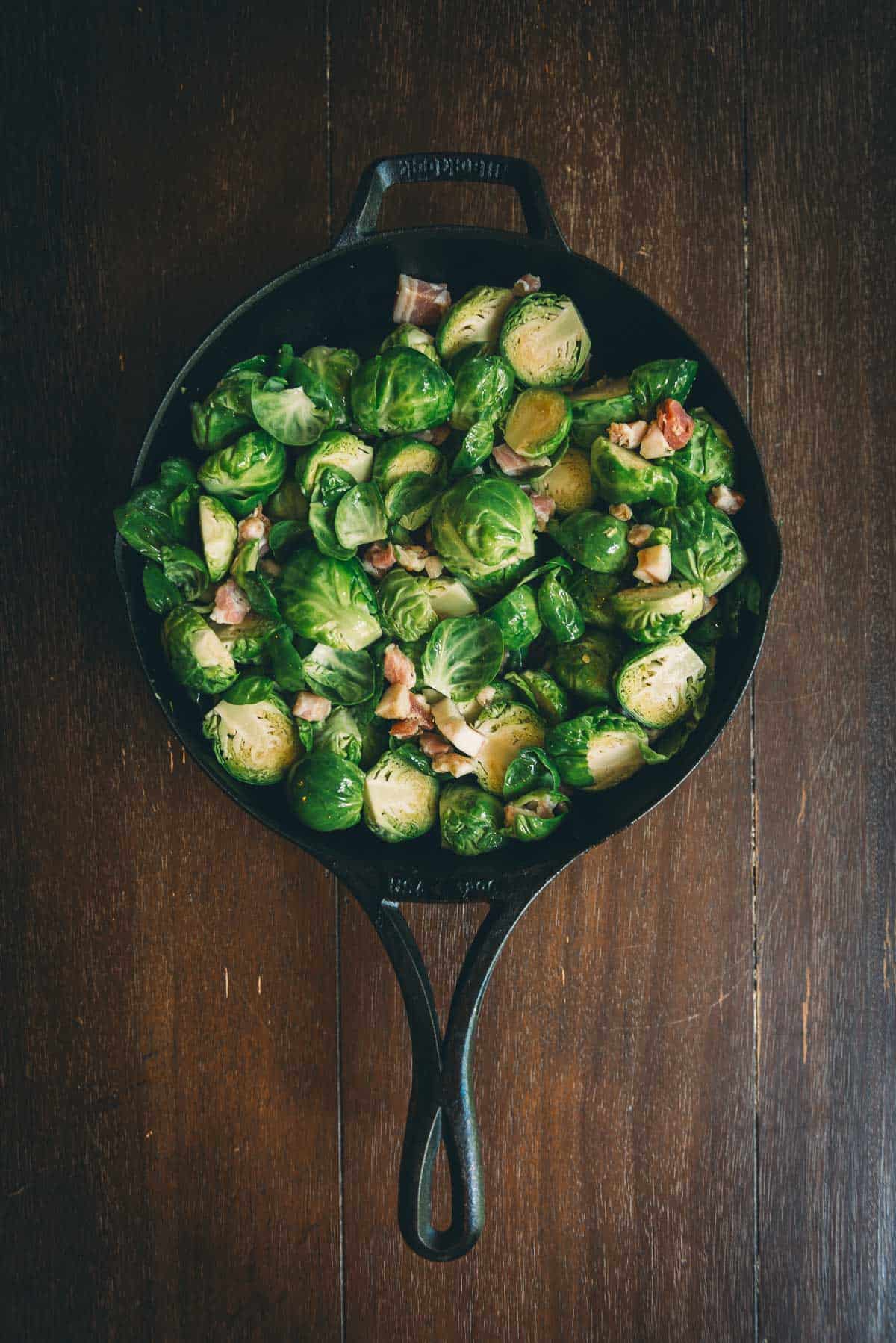 Brussels sprouts in a skillet on a wooden table.