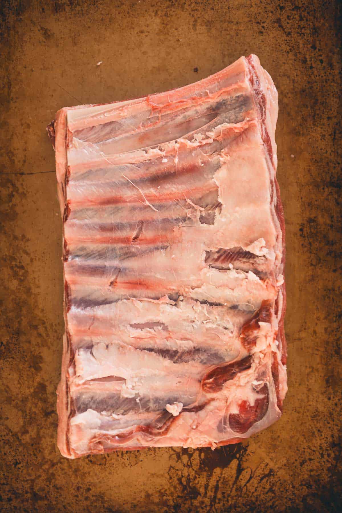 The back of a rack of lamb ribs to show the membrane removed.