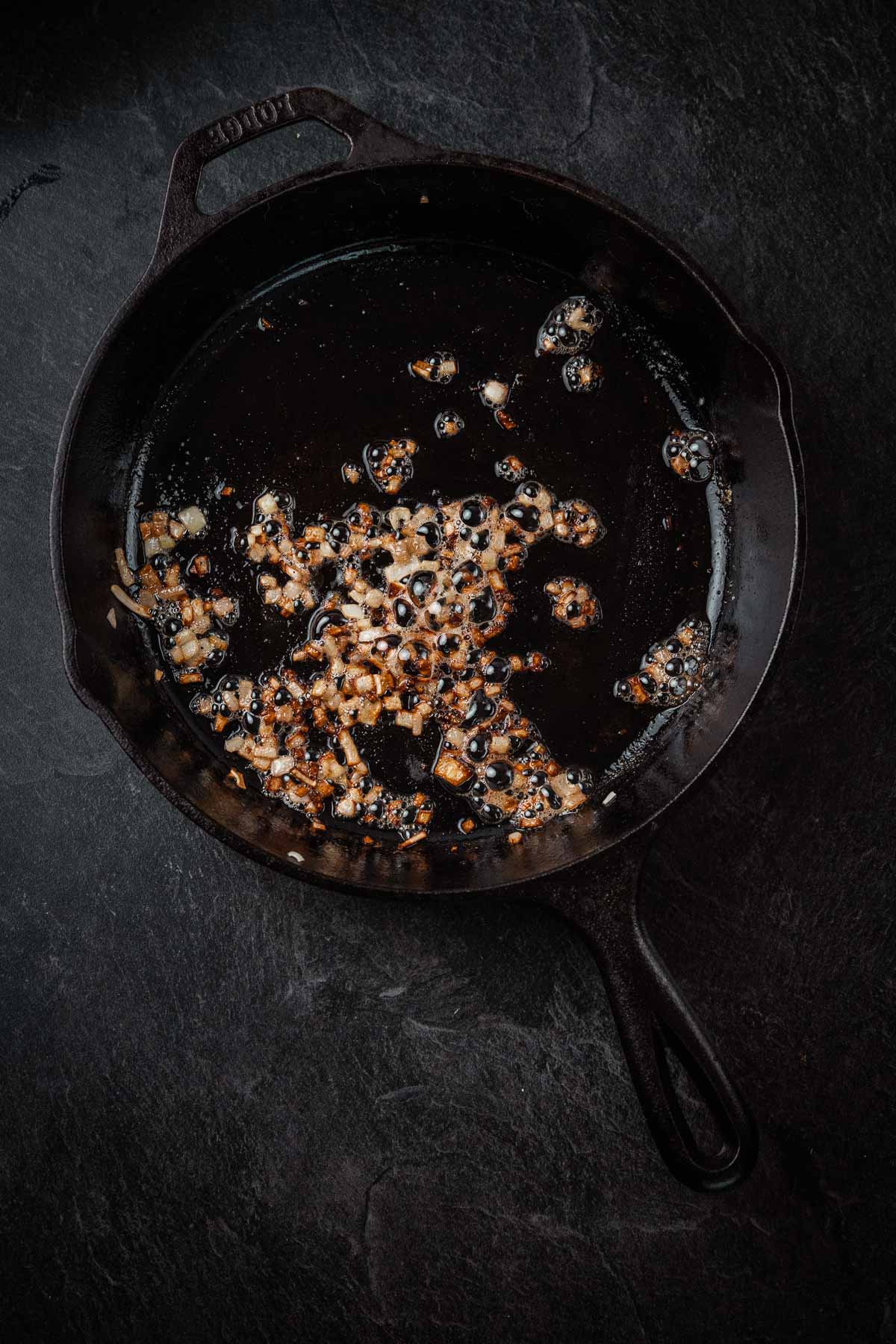A frying pan filled with oil on a dark background.