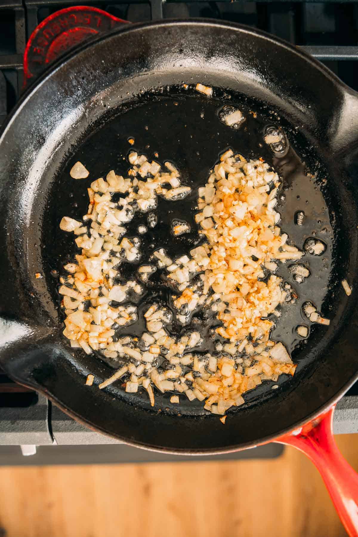 Fried onions in a skillet on a stove top.