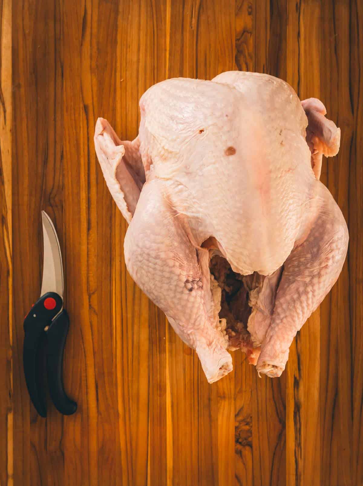 Raw turkey on a cutting board with sheers. 