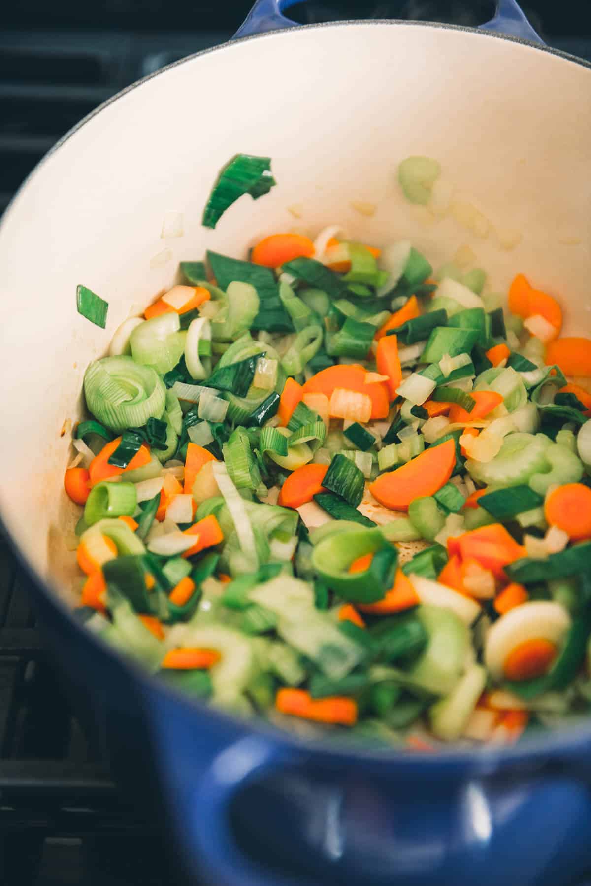 A pot full of vegetables on a stove top.