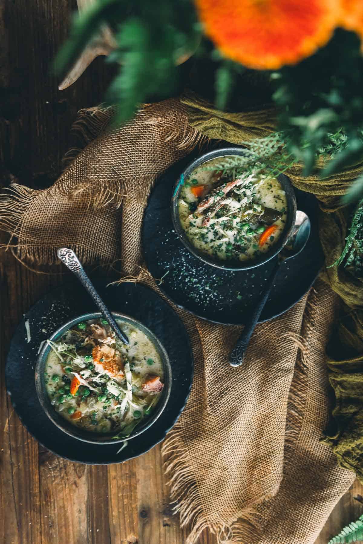 Two bowls of soup on a wooden table.