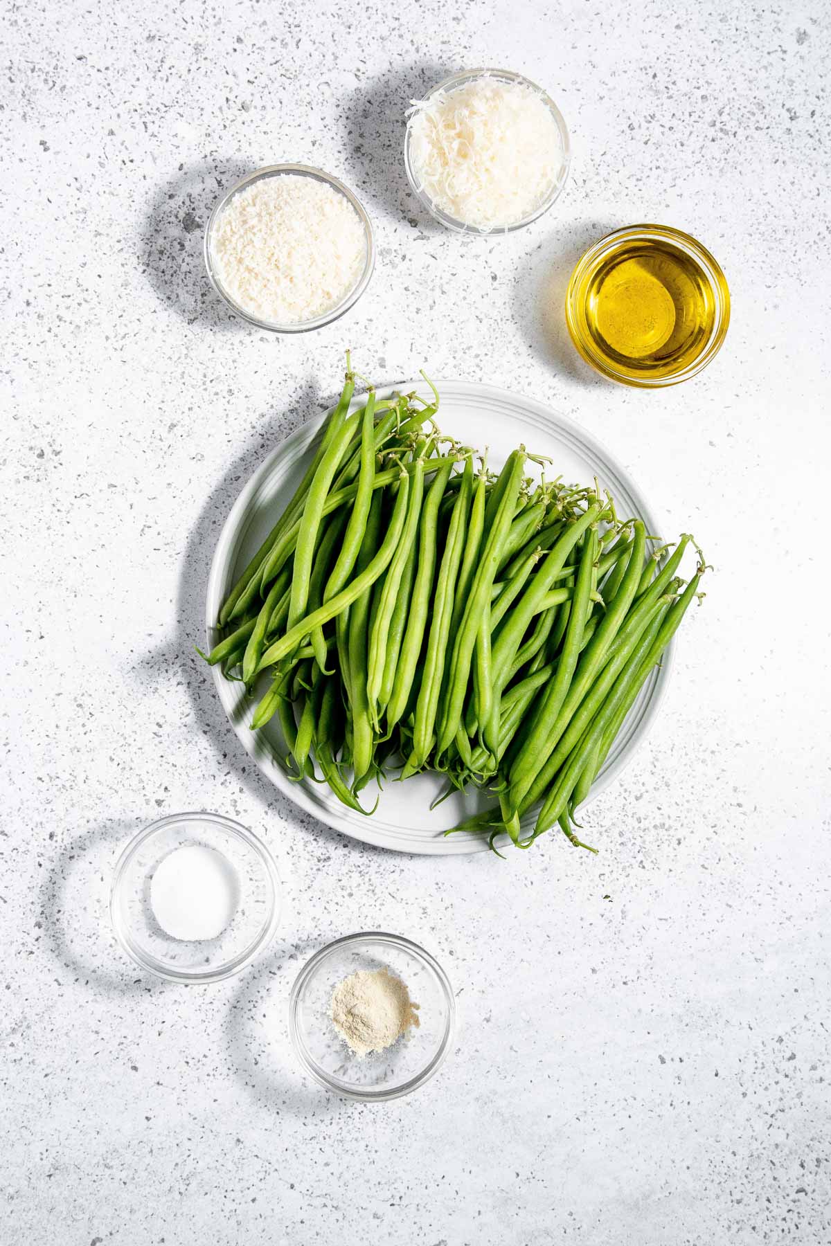 Green beans on a plate with olive oil, parmesan cheese, salt and pepper.