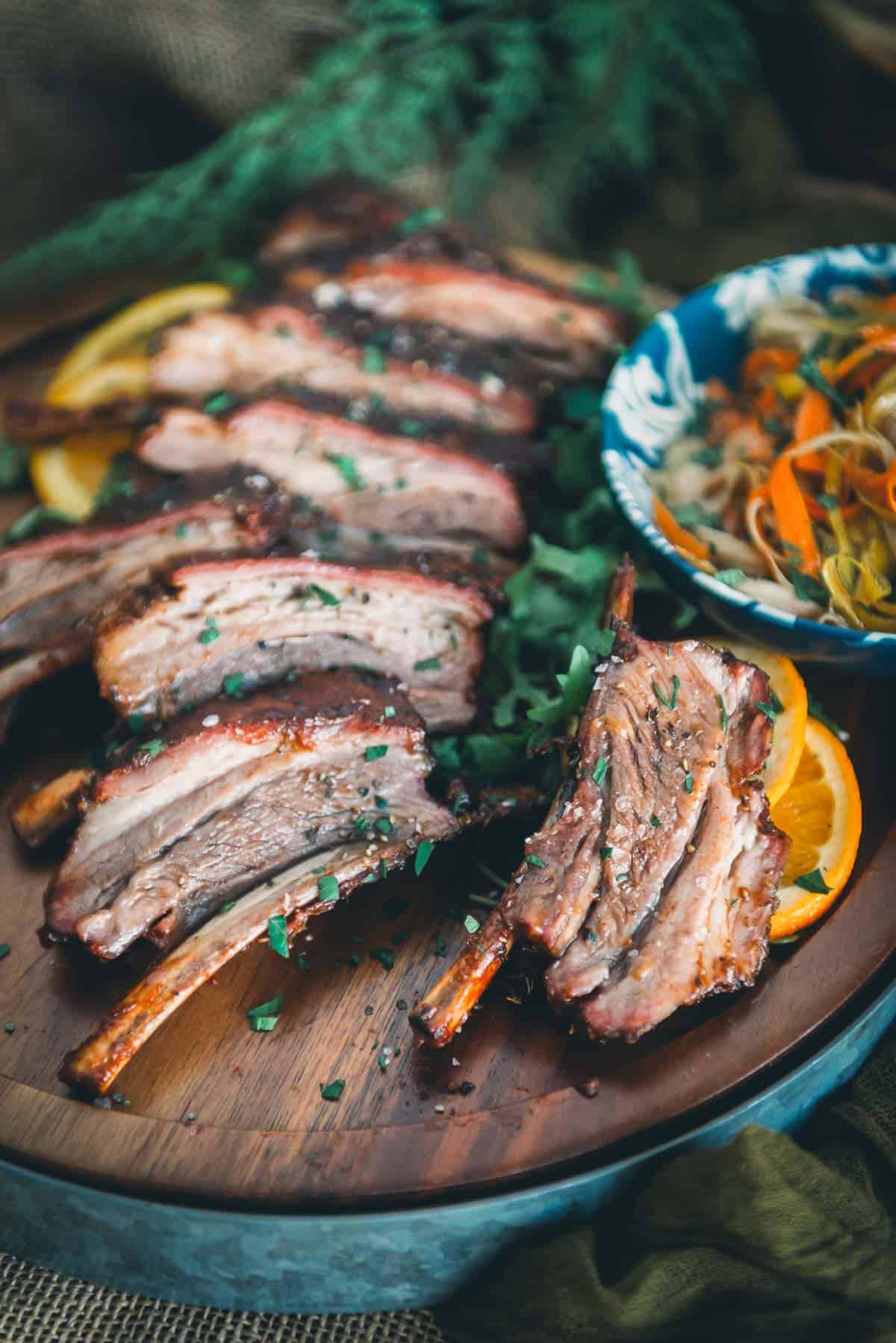 Bbq ribs on a wooden board with orange slices.