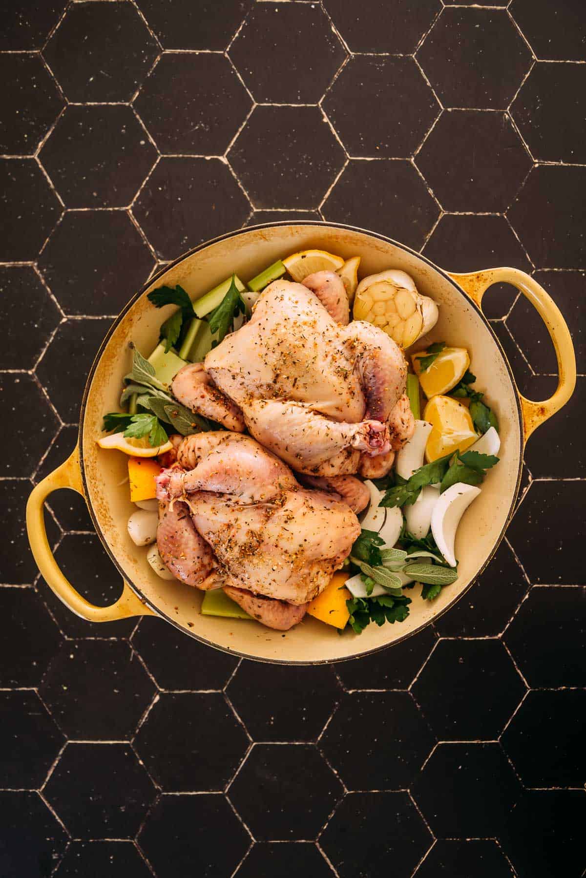 Cornish Hens in a pan on a black table.