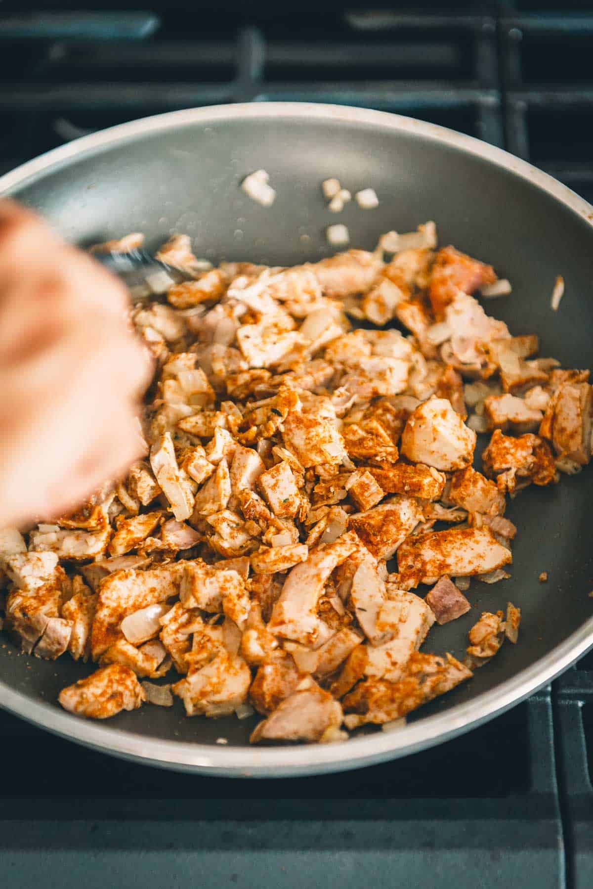 A person is cooking leftover turkey in a frying pan.