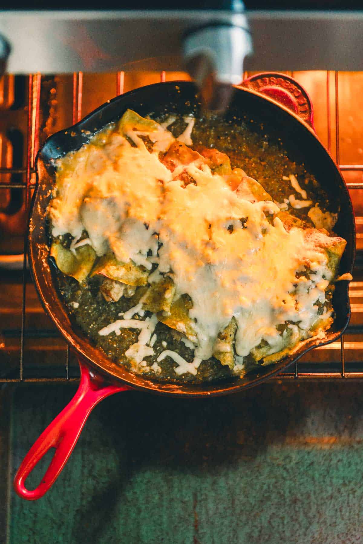 Cheesy enchiladas in a skillet coming out of the oven.