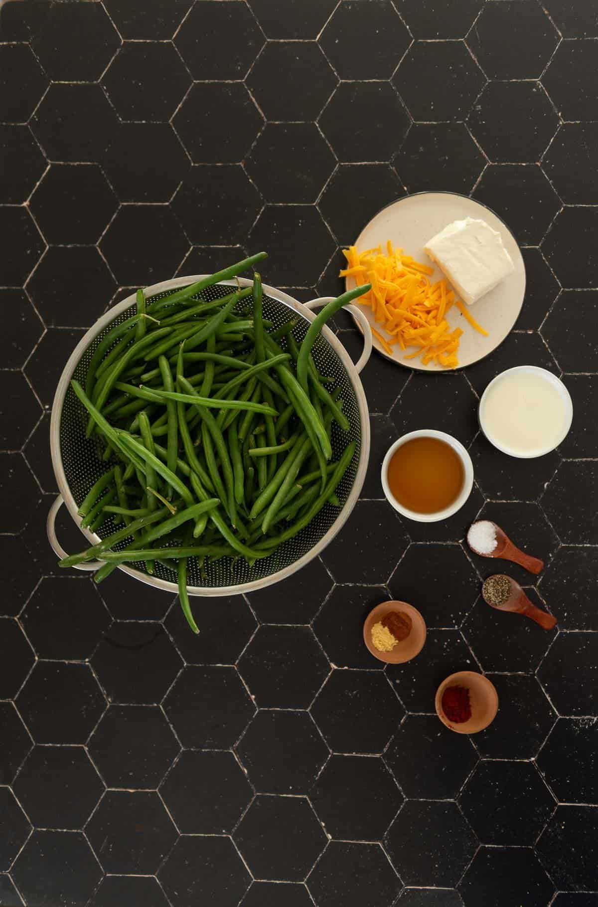 A bowl of green beans, cheese, and other ingredients on a black table.
