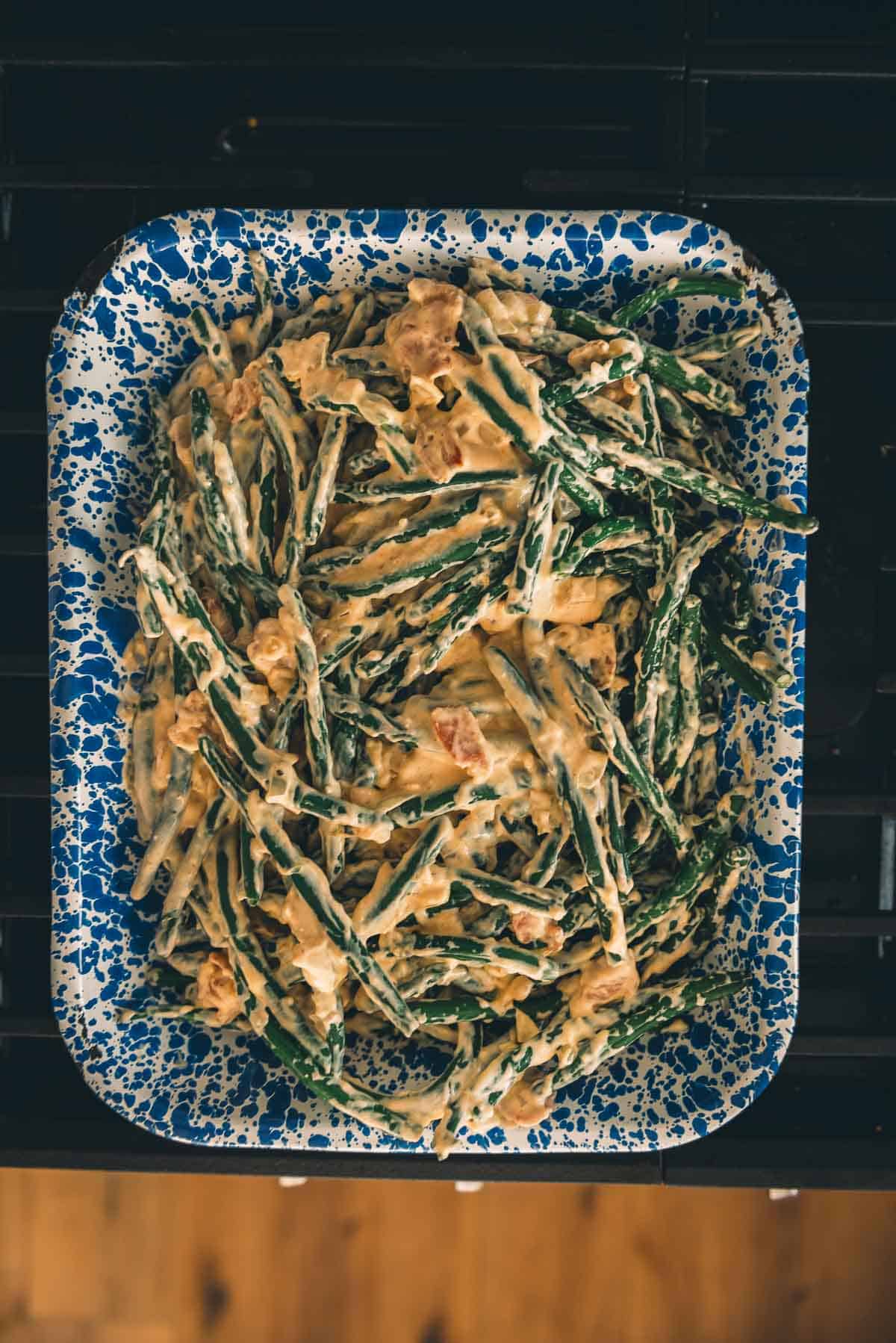 Green beans in a blue and white dish on a stove.