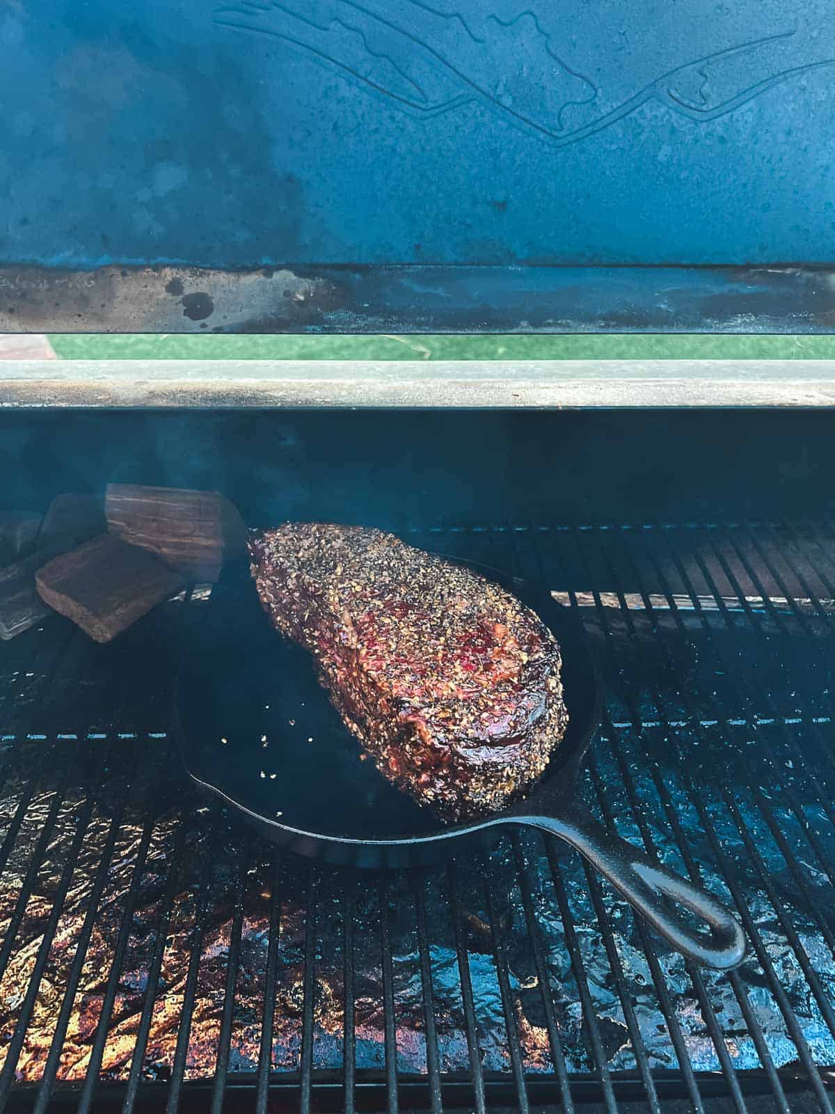 A rib roast is being seared in a cast iron skillet.