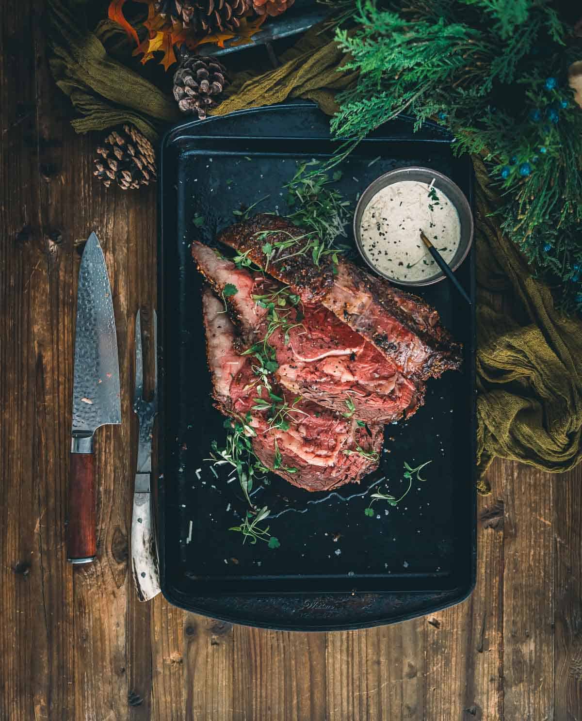 Steak on a baking sheet with herbs and spices.