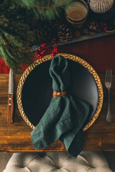 A plate with a napkin and fork on a wooden table.